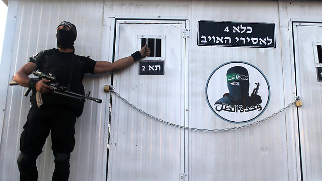 Hamas terrorist displays prison cell with words written in Hebrew, 'Prison for enemy prisoners' (Photo: Reuters)