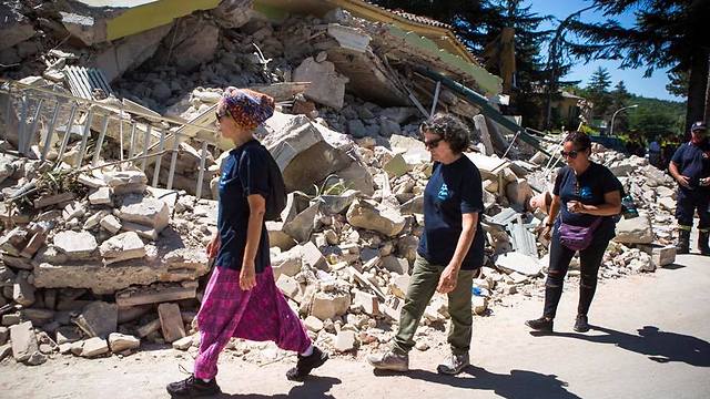 IsraAID workers walk by a destroyed building in central Italy (Photo: IsraAID)