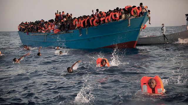 סירת מהגרים ליד חופי לוב. חלק קפצו למים ושחו לעבר מחלציהם (צילום: AP) (צילום: AP)