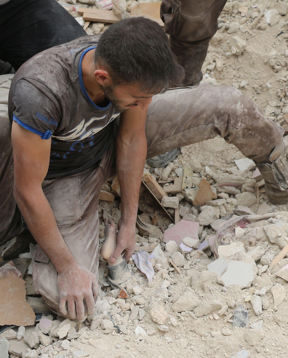 A man finds a child in rubble caused by a regime airstrike on Aleppo (Photo: AFP)