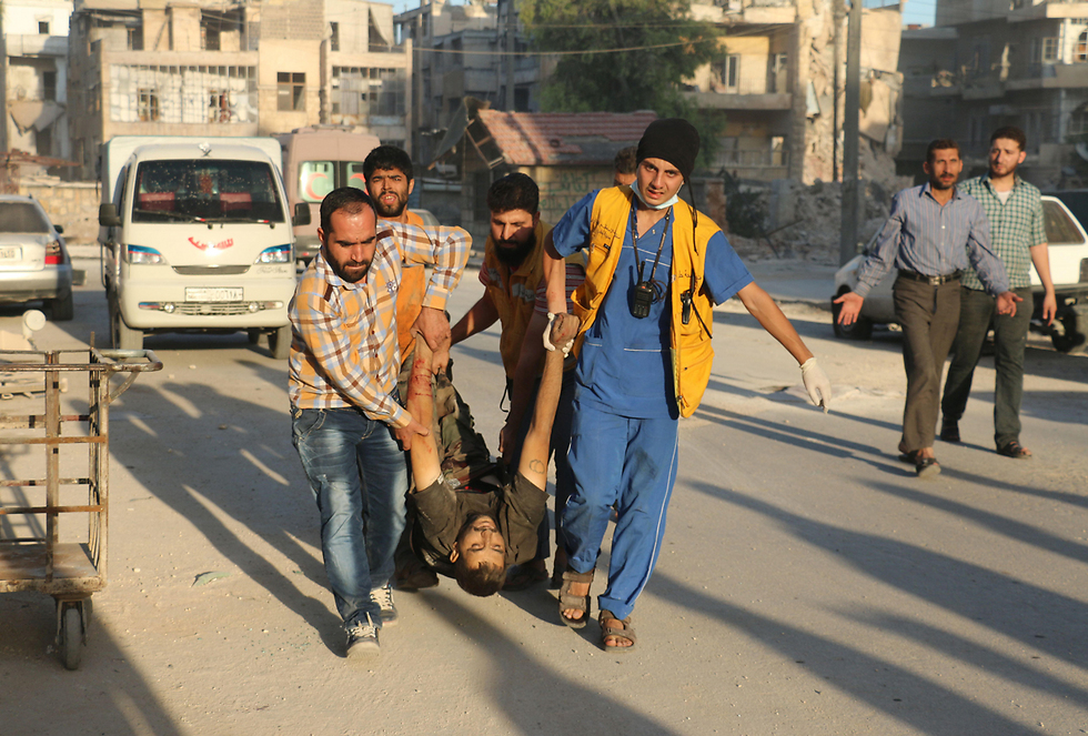 An injured man being carried to safety in Aleppo (Photo: AFP)