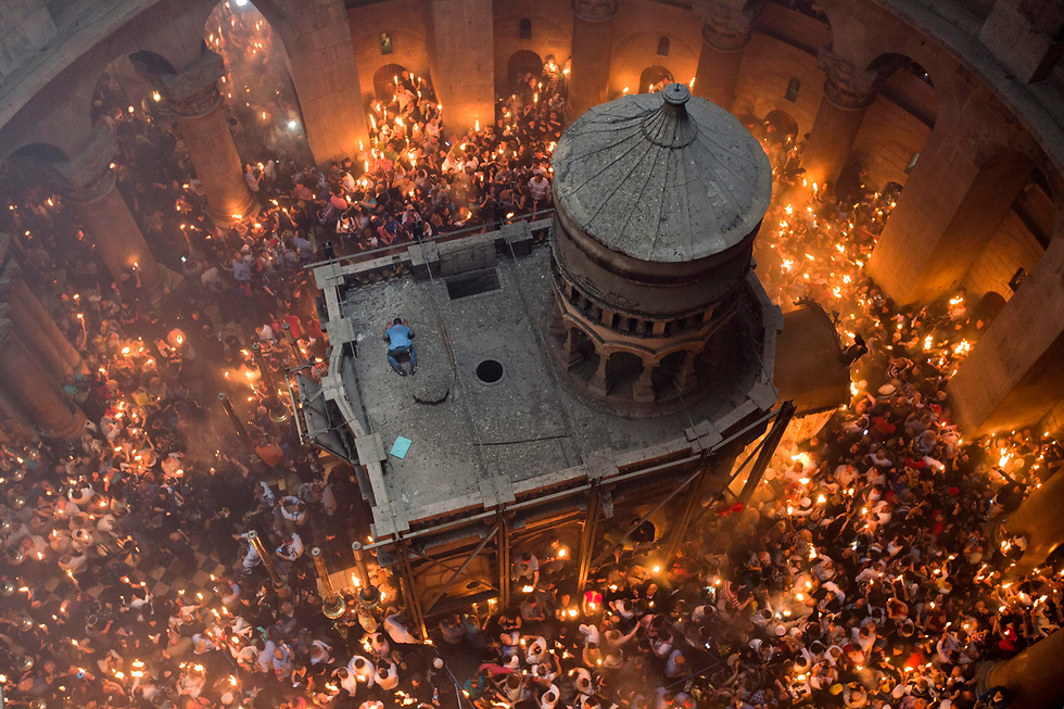 נוצרים מדליקים אש בטקס בכנסיית הקבר בירושלים (צילום: EPA) (צילום: EPA)