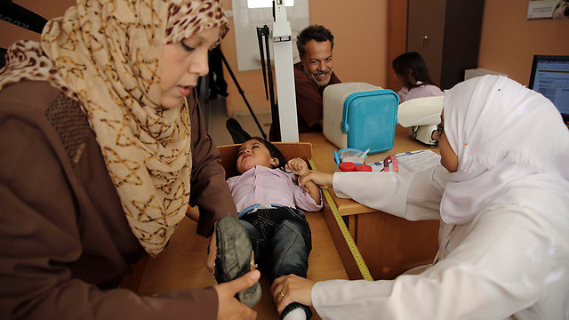 מנאל אל-עטר מסייעת לבנה עיסאם אצל רופא פלסטיני במרפאה של אונר"א (צילום: AP) (צילום: AP)