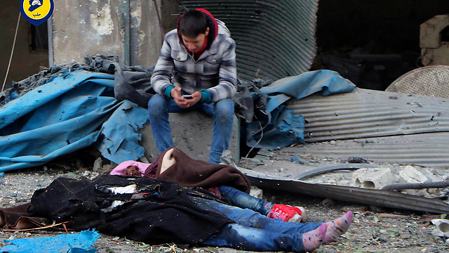 צעיר סורי בוכה ולידו שרועות גופות של ילדה ואישה בשכונת ג'וב אל-קובה בעיר חלב (צילום: AP) (צילום: AP)