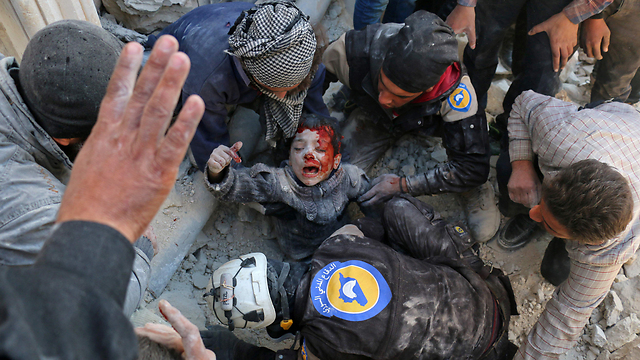 A wounded child being pulled out of the rubble in Aleppo (Photo: AFP)