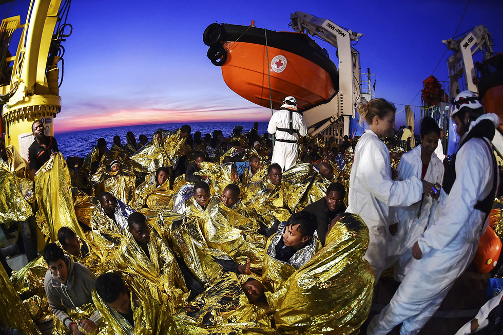 מהגרים עטופים אחרי שנמשו מהמים, כשספינתם טבעה מול חופי לוב (צילום: AFP) (צילום: AFP)