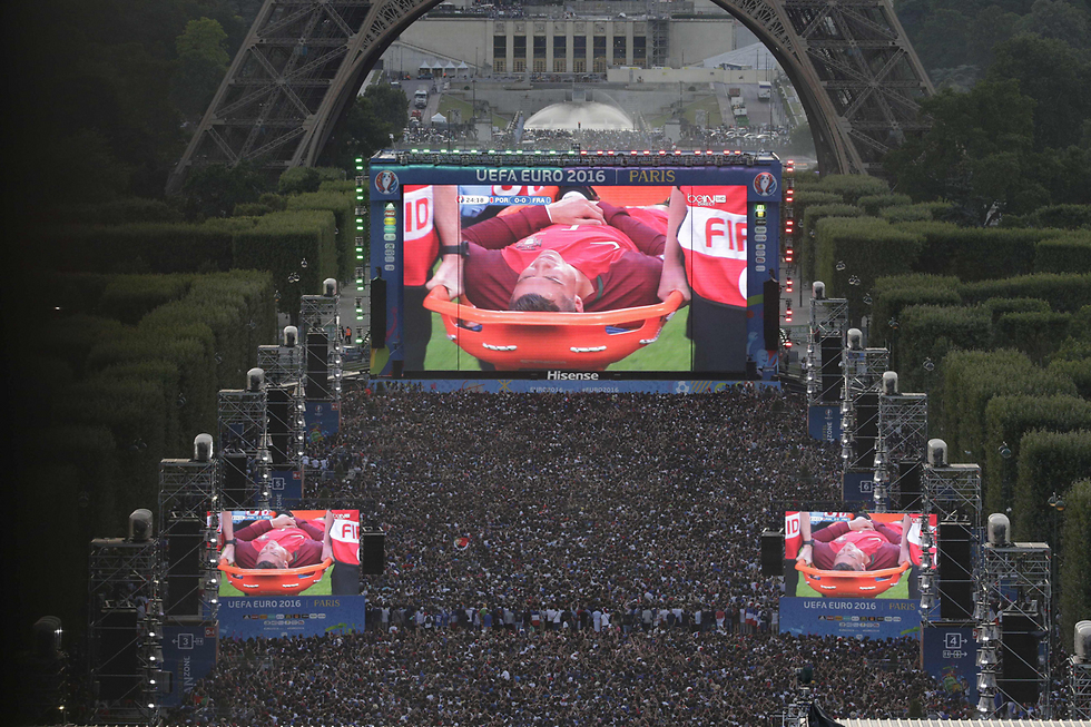אלפים צופים בגמר אליפות אירופה בכדורגל בפריז, בדיוק ברגע שבו כוכב העל כריסטיאנו רונאלדו מפונה פצוע מהמגרש. פורטוגל הדהימה וניצחה בלעדיו את צרפת המארחת 0:1 (צילום: AFP) (צילום: AFP)