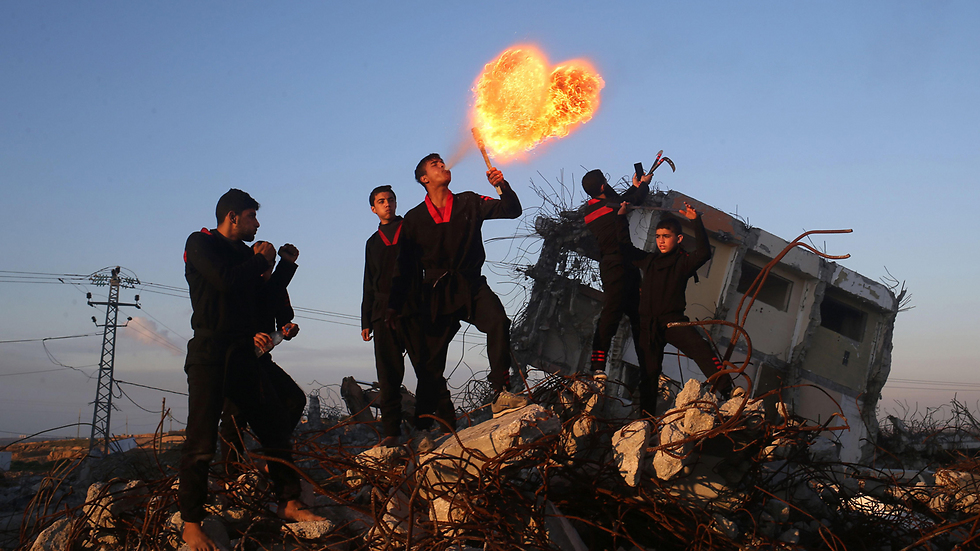 פלסטיני, מתמחה באומנויות לחימה, מבעיר אש על הריסות בית בבית חאנון שברצועת עזה (צילום: AFP) (צילום: AFP)