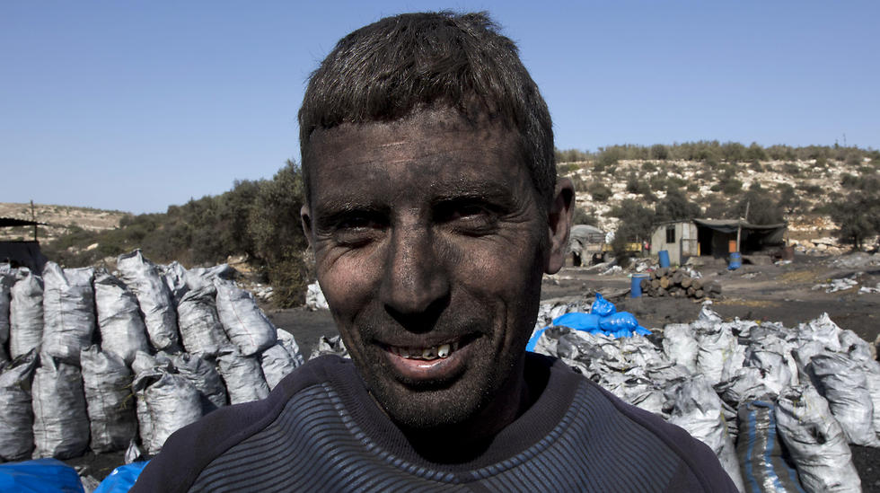 Palestinian laborer Sami Abu Baker, 35, who has a fifteen years service in the charcoal factories, poses for a picture during work (Photo: AP)