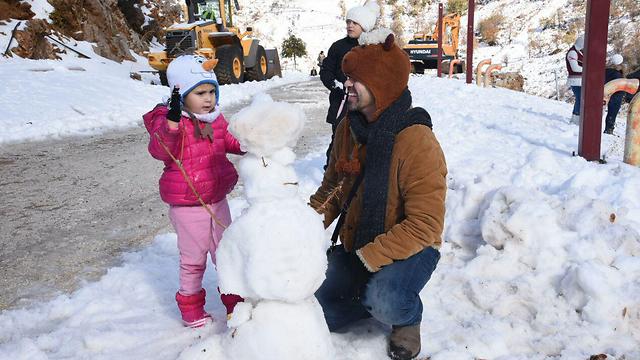 A man and his daughter build a snowman on Mt. Hermon (Photo: Aviyahu Shapira)