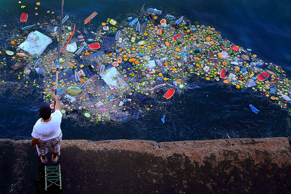 A man fishes amongst garbage off the coast of Beruit, Lebanon (Photo: AP)