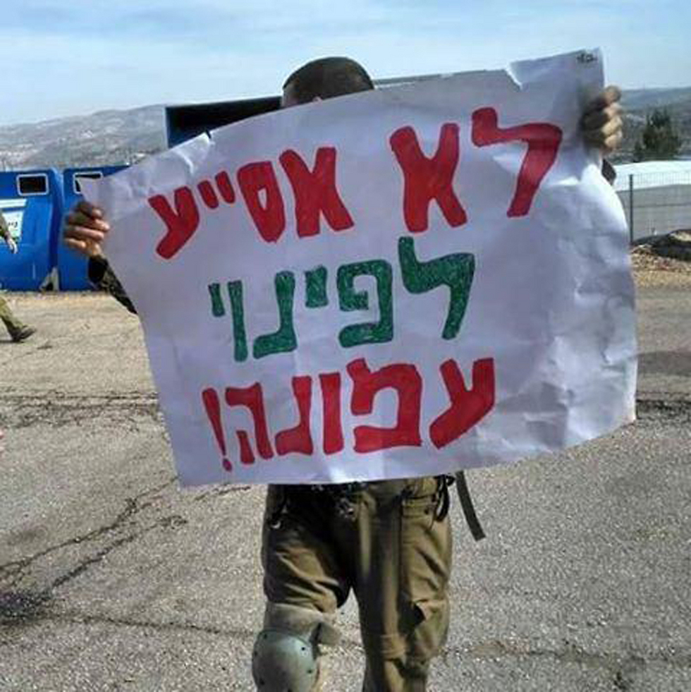 IDF soldier holds sign reading: 'I won't assist in the evacuation of Amona'