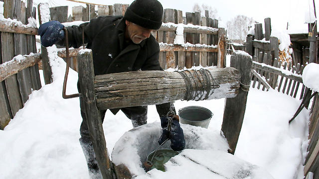 מיכאיל שואב מים מהבאר בחורף המושלג של סיביר (צילום: רויטרס) (צילום: רויטרס)