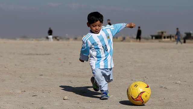 ילד אפגני משחק כדורגל, לבוש בחולצה חתומה שקיבל מכדורגלן העל ליונל מסי (צילום: רויטרס) (צילום: רויטרס)