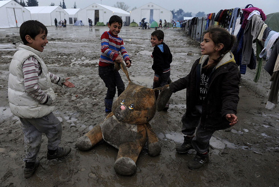 ילדות שנשדדה: ילדים פליטים מהמזרח התיכון משחקים בדובי מלוכלך במחנה פליטים בגבול יוון-מקדוניה (צילום: רויטרס) (צילום: רויטרס)