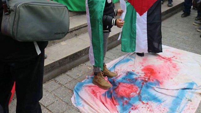 Demonstrators stepping on the Israeli flag in response to a-Zawahri's assasination