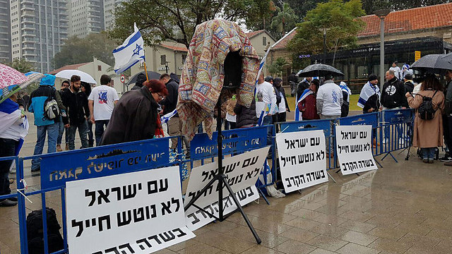 Protesters who arrived early waiting behind the barricades with signs that say 'The people of Israel don't abandon a soldier during battle' 