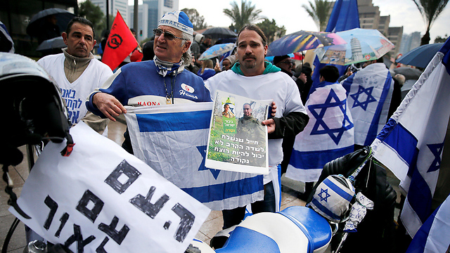 Protesters holding signs and Israeli flag, with one banner saying 'The people are with you Elor' (Photo: Reuters)