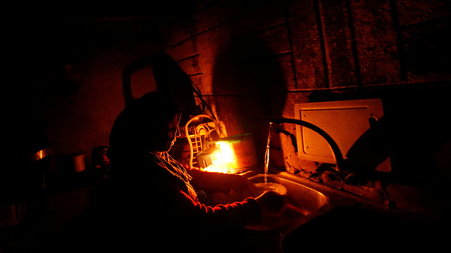 A Gazan woman washes dishes in the dark (Photo: Reuters)