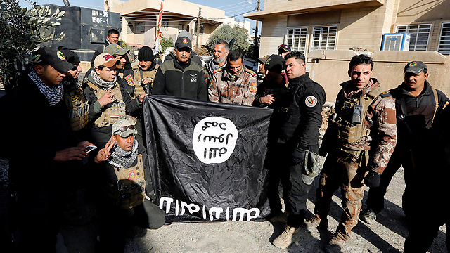 צבא עיראק עם דגל דאעש במוסול. בארגון מבטיחים להמשיך להילחם (צילום: רויטרס) (צילום: רויטרס)