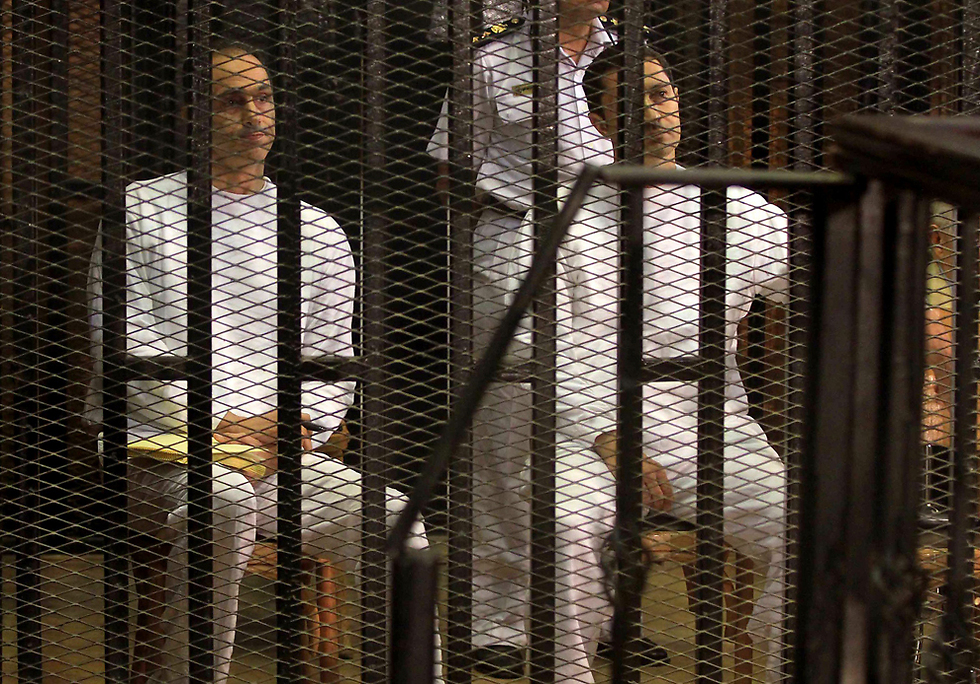 מימין לשמאל: האחים עלאא וגמאל מובארק מאחורי הסורגים בעת דיון במשפטם (צילום: AFP) (צילום: AFP)