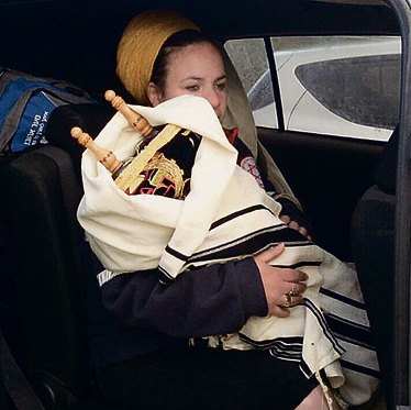 Na'ama Ben-Hemo clutching the Torah scrolls close as she leaves Amona (Photo: Odaya Van Luan)