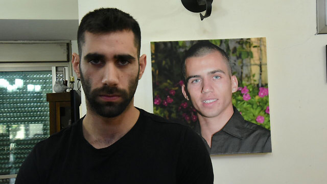 Aviram Shaul with his brother’s picture in the background. ‘If it happened today, I definitely wouldn’t sit shiva’  (Photo: Avihu Shapira)