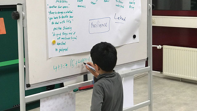 A Syrian boy makes use of the white board at the workshop for his studies