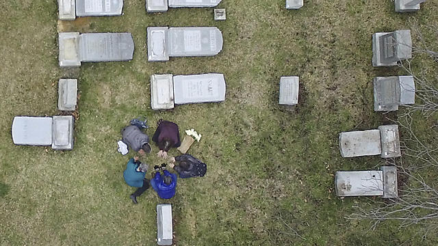 People gather in prayer amid the toppled headstones (Photo: AP)