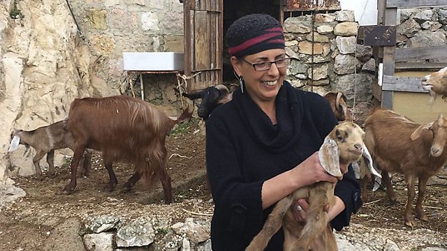 Efrat Giat holding a baby goat in the backyard of her home in Ein Kerem (Photo: Madison Dudley/The Media Line 