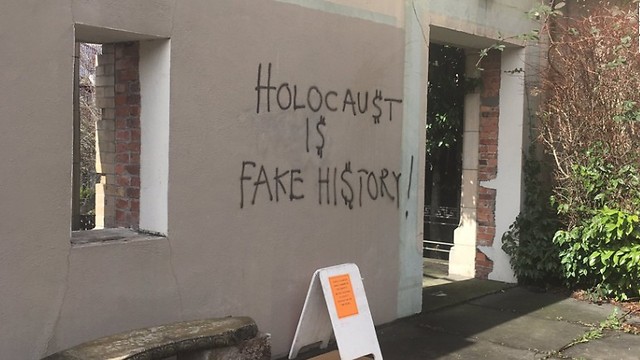 An exterior wall of the synagogue, spray-painted with a Holocaust denying message (From Twitter)