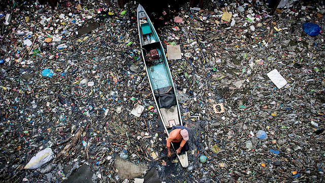 עובד אוסף זבל מנהר מרילאו בצפון הפיליפינים  (צילום: AFP) (צילום: AFP)