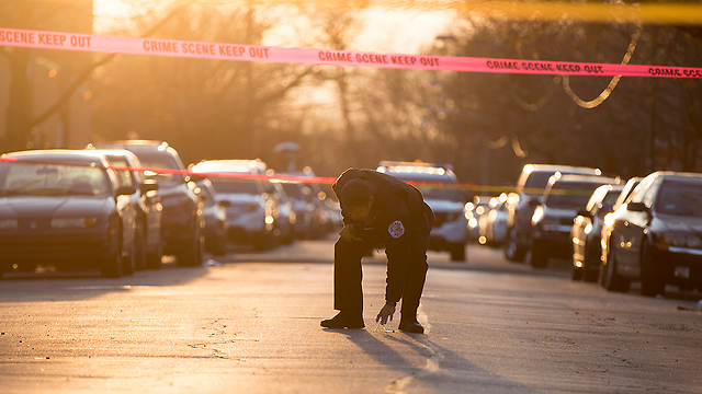 העיר המדממת ביותר בארה"ב. שוטר בוחן זירת ירי בשיקגו (צילום: MCT) (צילום: MCT)