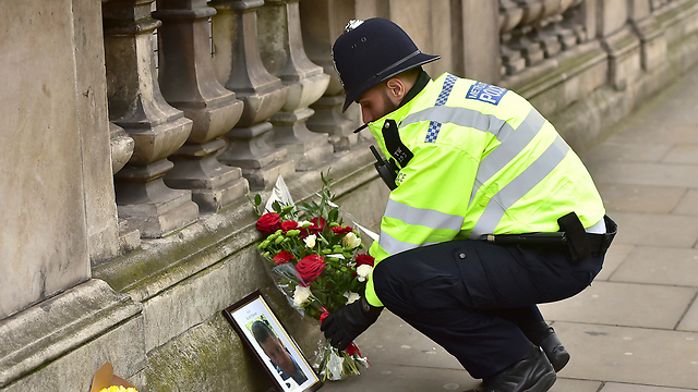 שוטר מניח פרחים לזכר עמיתו שנרצח קית' פאלמר (צילום: AP) (צילום: AP)