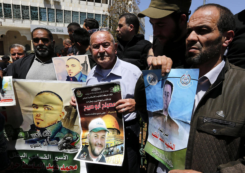 Palestinians hold pictures of their relatives held in Israeli jails during a supportive rally calling for the release of Palestinian prisoners in Israel, in the West Bank city of Hebron on Monday (Photo: EPA)