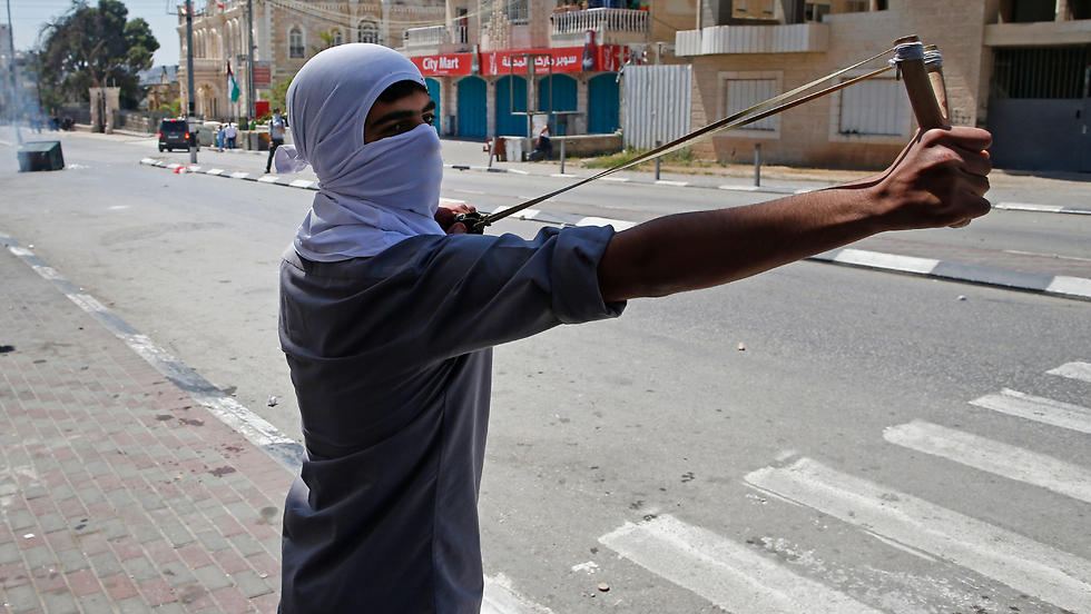 A Palestinian protester uses a sling shot to hurl towards Israeli security forces during clashes following a demonstration in the West Bank town of Bethlehem. (Photo: AFP)