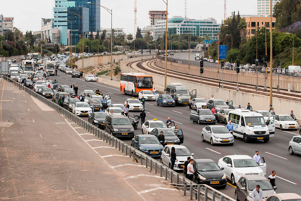 Drivers leave their cars to stand at attention during the 2-minute siren (Photo: AFP)