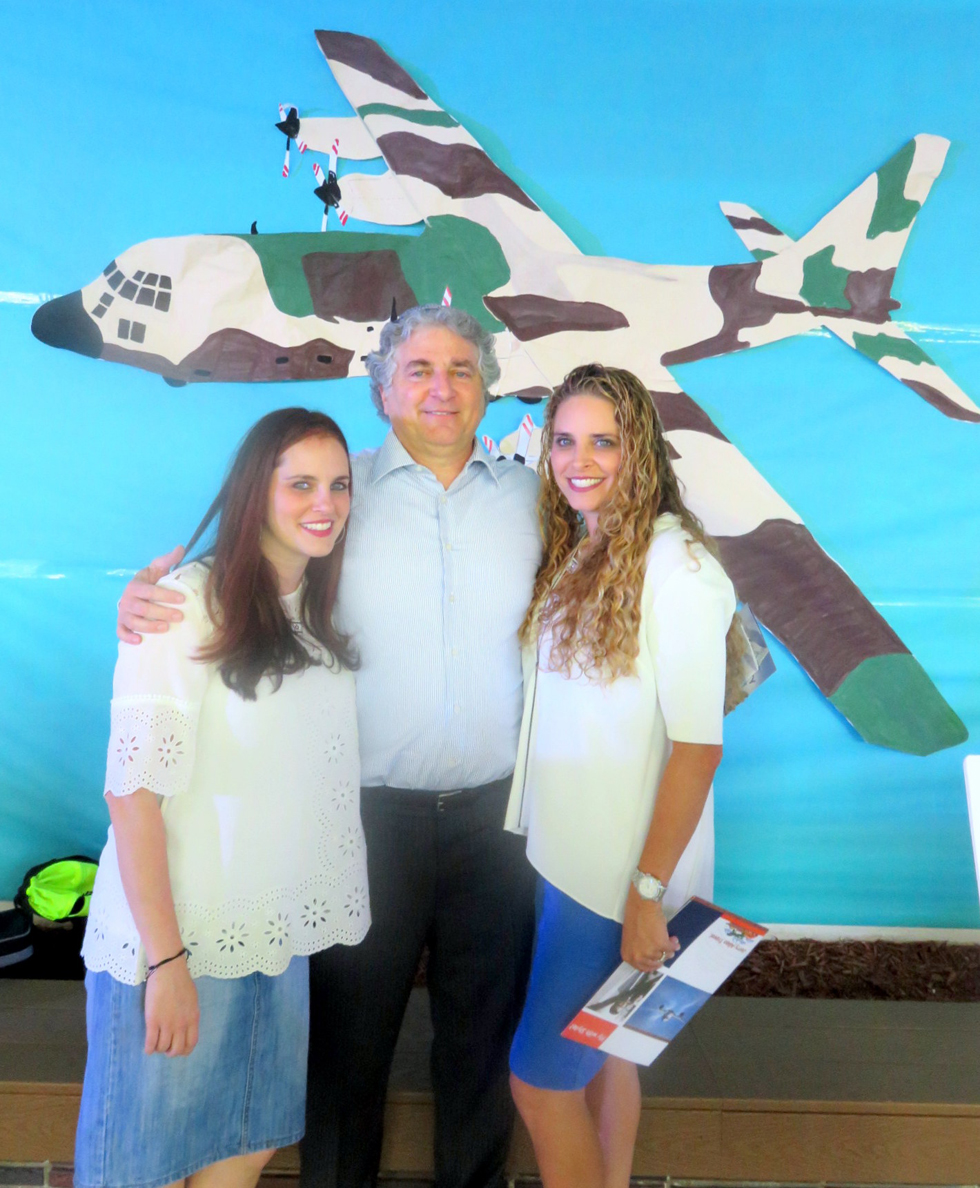 סיימון פאליק ובנותיו תילה וליסה, כשברקע מטוס ה"הרקולס" שהשיב את חטופי אנטבה ()