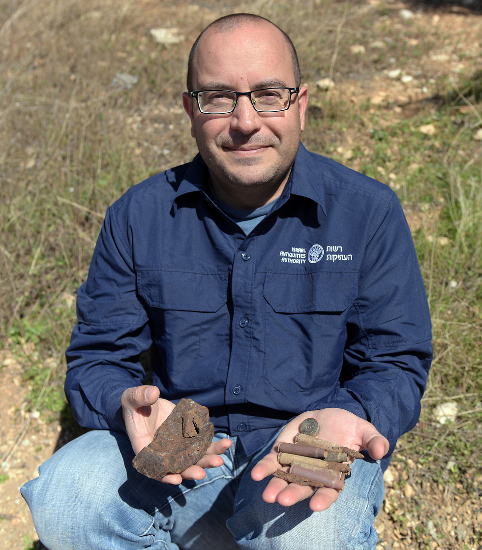 Assaf Peretz with some of the military finds discovered at the site. (Photo: Clara Amit, IAA)
