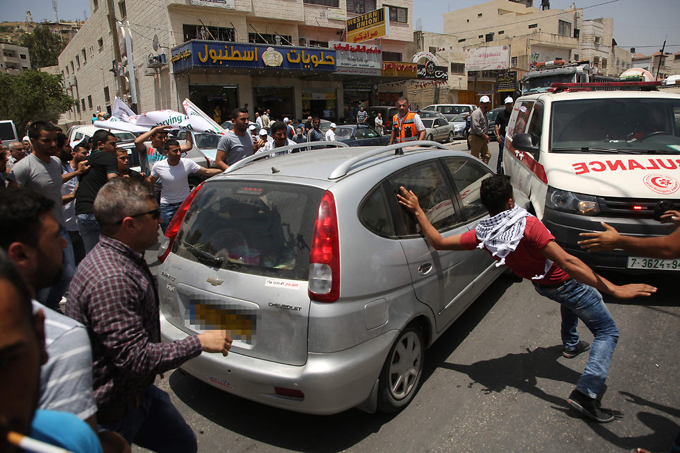 אמבולנס חוסם את רכבו של היהודי ומסביב ההמון (צילום: AFP) (צילום: AFP)