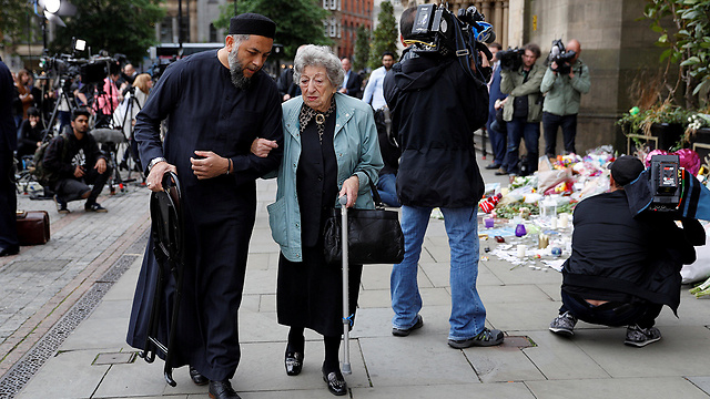 המוסלמי סאדיק פטל מסייע לקשישה היהודייה רנה רייצ'ל בלאק במנצ'סטר (צילום: רויטרס) (צילום: רויטרס)