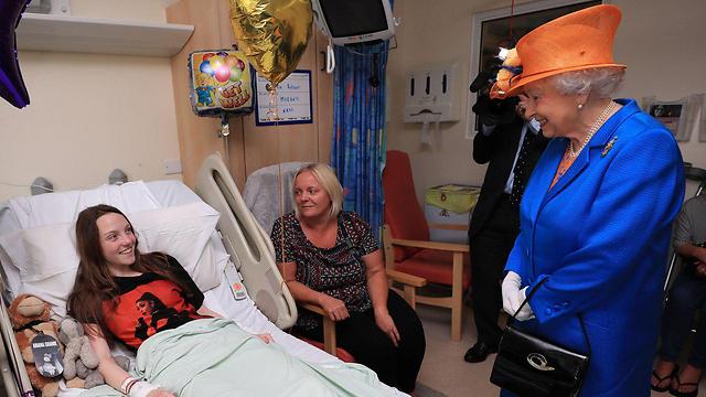 המלכה אליזבת מבקרת את מילי רובסון, בת 15 שנפצעה בפיגוע, ואמה מרי (צילום: AFP) (צילום: AFP)