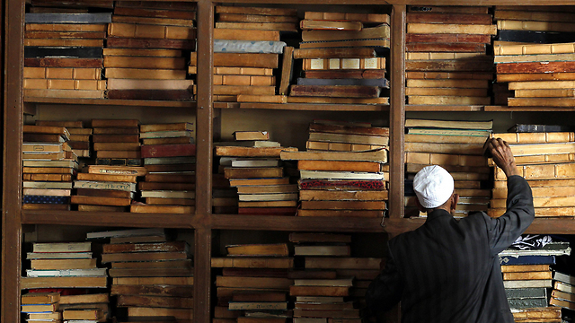 מוסלמי שולף עותק של הקוראן מהמדף בצנעא, תימן (צילום: EPA) (צילום: EPA)