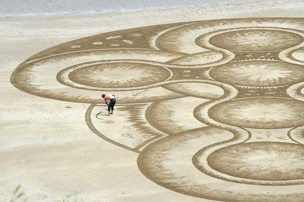 אמן החול מרק טרינור עם יצירה חדשה בחוף הים בטנבי הרבור, ויילס (צילום: רויטרס) (צילום: רויטרס)