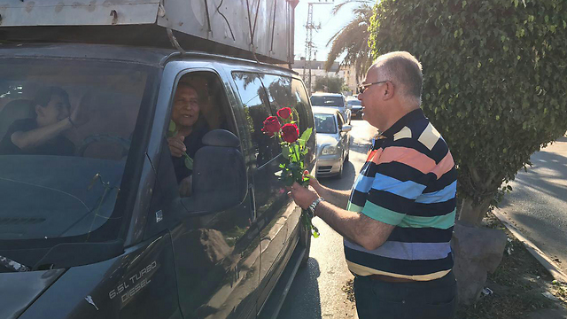 Tayibe Mayor Sha'a Mansour Massarwa hands out flowers to residents 