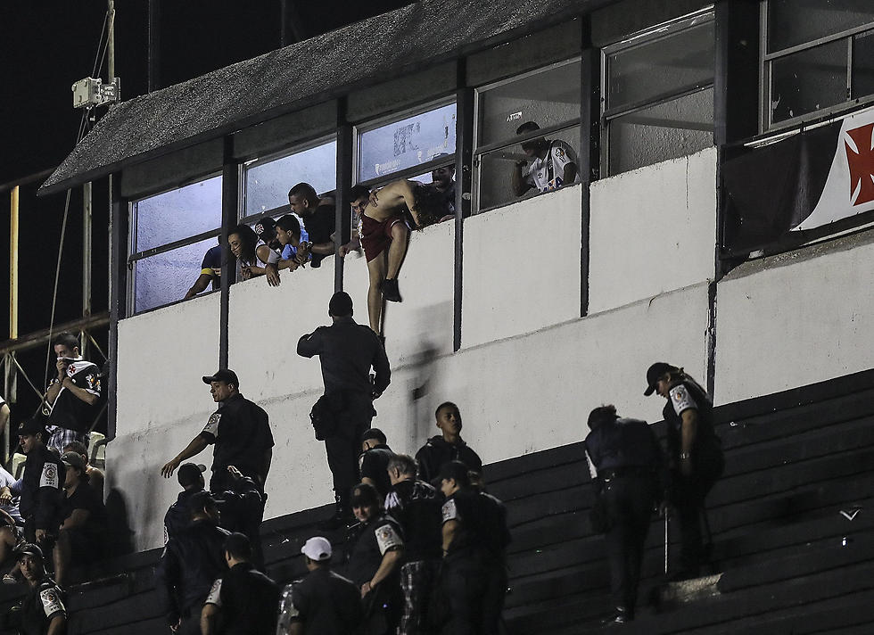 אוהד מנסה להימלט מהשוטרים (צילום: EPA) (צילום: EPA)