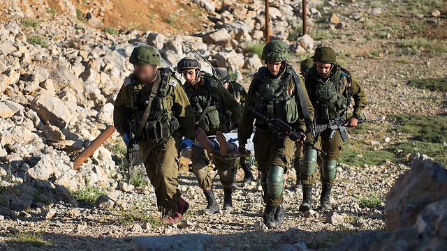 A wounded Syrian is carried by IDF troops to treatment (Photo: IDF Spokesperson's Unit)