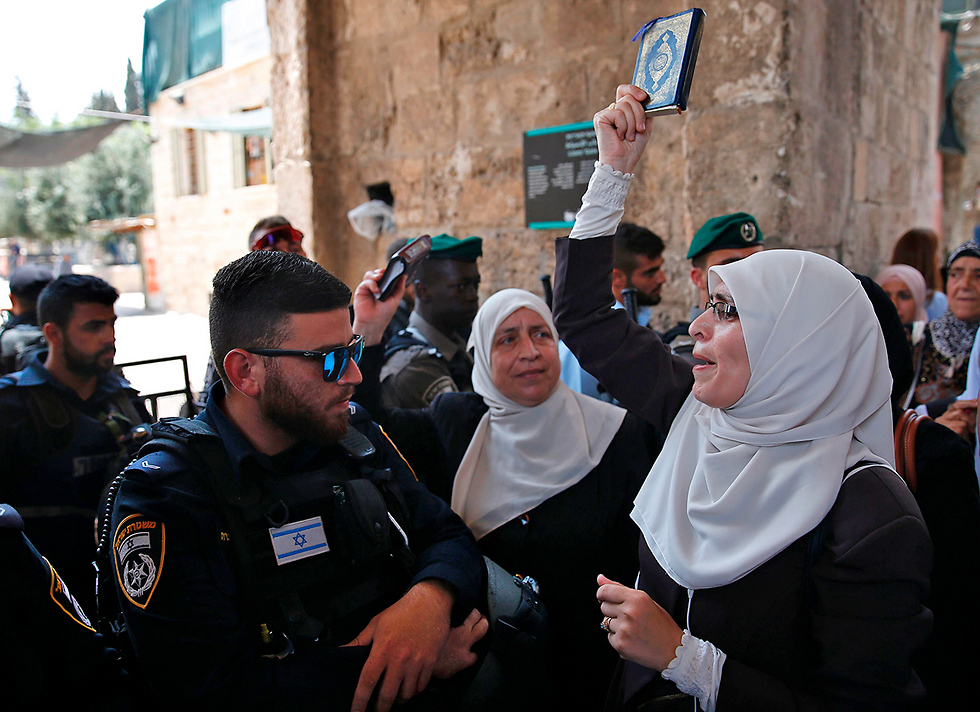 פלסטינית נופפה בקוראן בפני שוטר בעיר העתיקה  (צילום: AFP) (צילום: AFP)