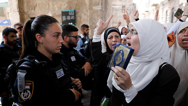 A Muslim protestor waves the Quran in front of an IDF police woman (Photo: EPA)