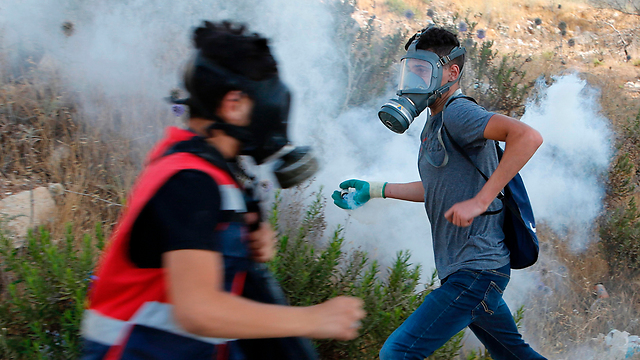 Palestinian rioters attempt to throw tear gas canisters back at police (Photo: AFP)